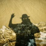 Shadow of a person in a hat waving on sand
